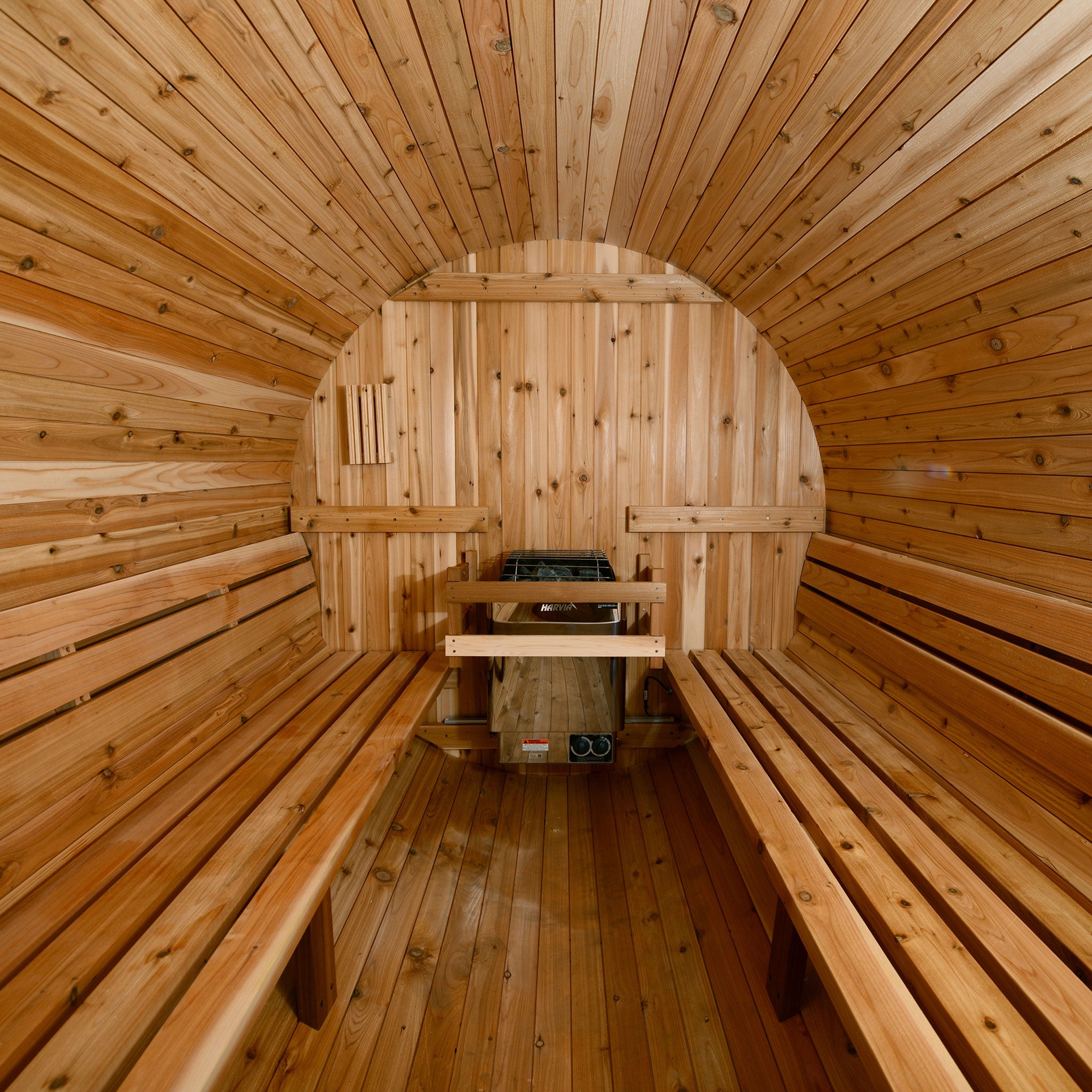 Barrel sauna interior with horizontal slat bench design and Harvia heater.